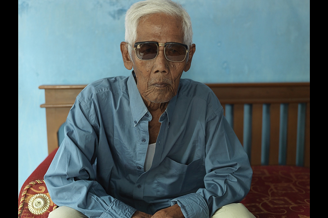Bapak Saih bin Sakam, born 16 April 1923, the only living survivor of the massacre: `We were shot from the back, from a distance of about 2,5 meters. The man behind me was shot dead, the bullit went right through his body and hit my back. The man fell upon me and I felt his blood running over my face. When they left they shot again every body, to be sure we were all dead. They shot me through my hand. I was one of fourteen men who survived. My father, who was in the same line as I, was killed`. 